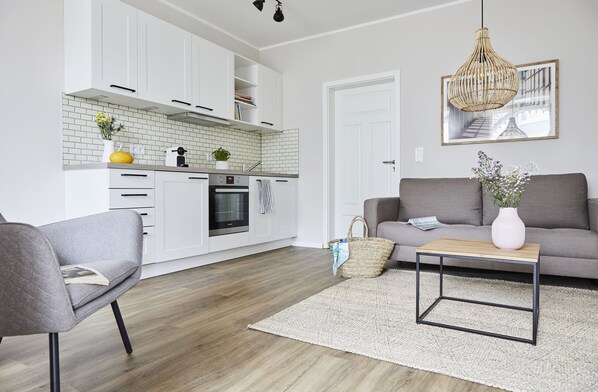 A modern kitchen with white cabinets, a wooden countertop, and a hanging light fixture.
