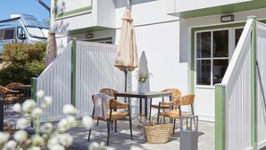 A patio with a table and chairs, a hanging umbrella, and a white fence. - Villa Fortuna (Sellin)