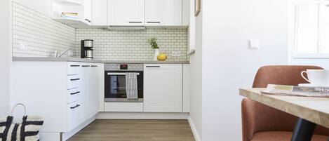 Una cucina moderna con mobili bianchi, una macchina per il caffè e una piccola pianta sul piano di lavoro.