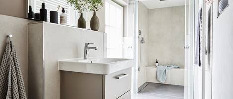 Un baño moderno con un espejo grande, un lavabo y una zona de ducha.