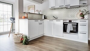 A modern kitchen with white cabinets, a tiled backsplash, and a built-in oven. - Villa Fortuna (Sellin)