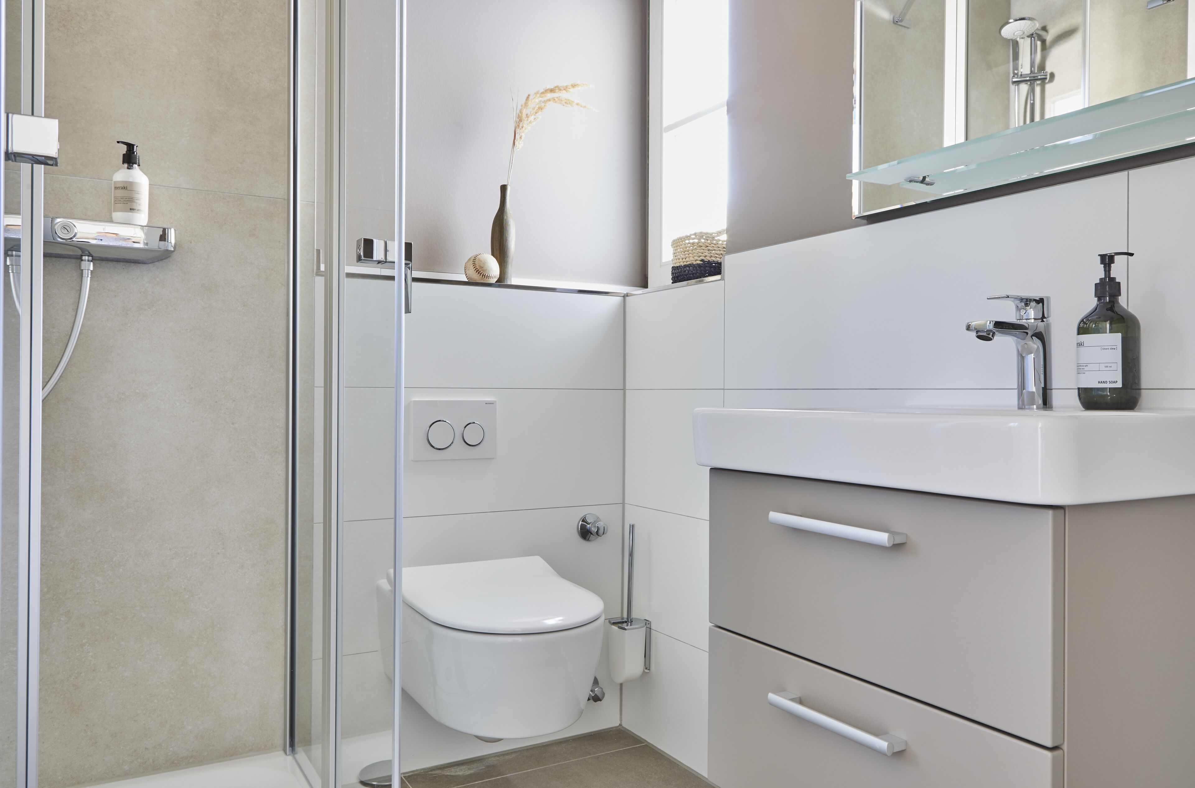 A modern bathroom with a glass shower enclosure, a toilet, a sink with a mirror, and a small shelf with toiletries.