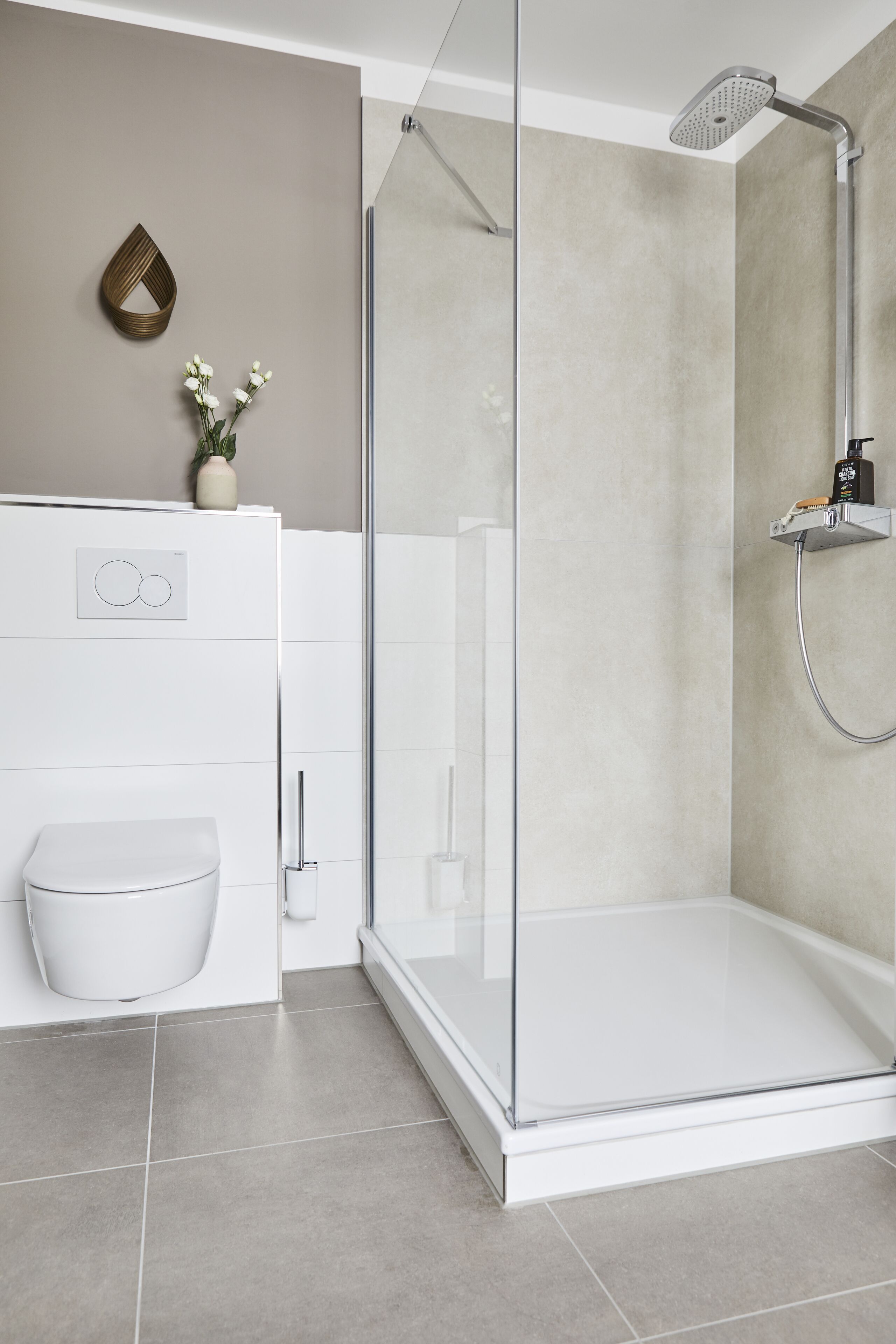A modern bathroom with a glass-enclosed shower, a white toilet, and a small decorative vase on the wall.