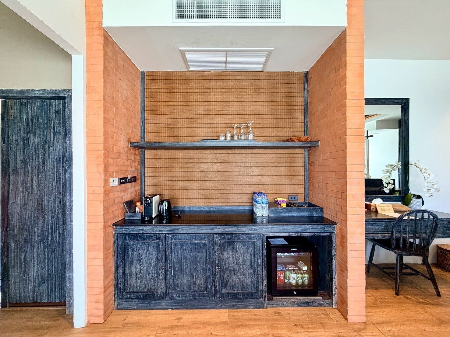 A compact kitchen with a built-in refrigerator, a coffee machine, and a water dispenser.