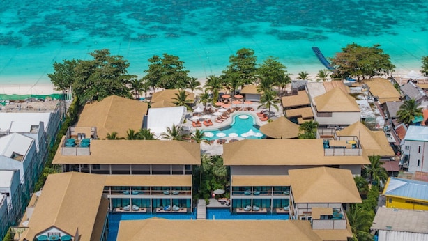 Un resort con piscina central, varias habitaciones de huéspedes y vista al mar.