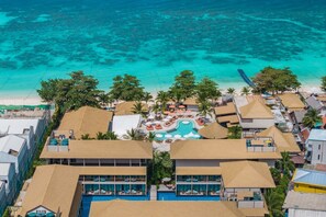 A resort with a central pool, multiple guest rooms, and a beach view.