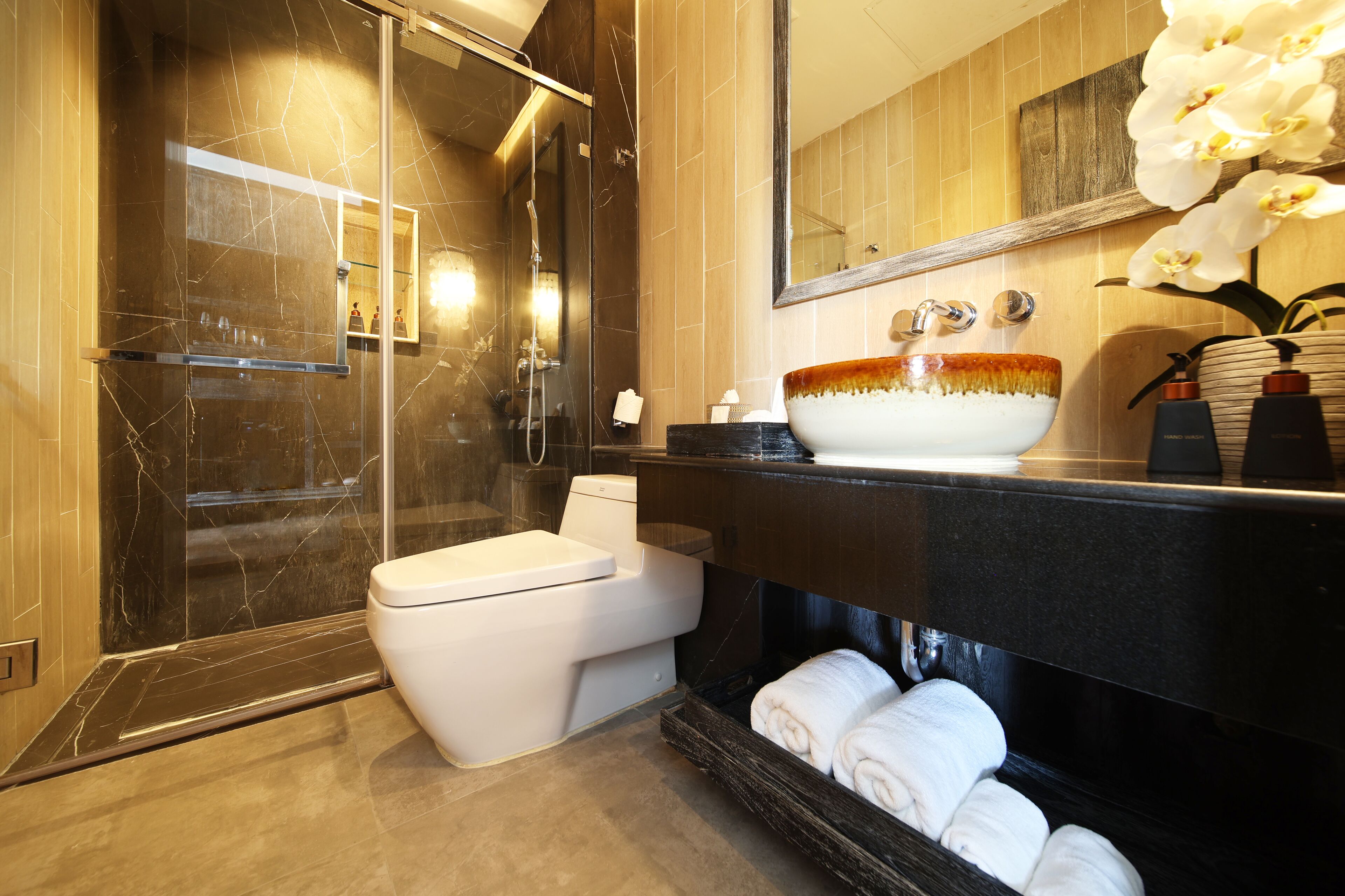 A modern bathroom with a glass-enclosed shower, a white toilet, and a large vessel sink.
