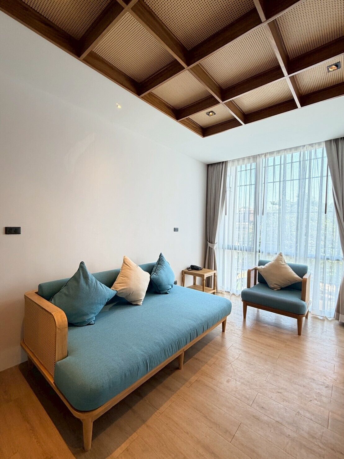 A modern living room with a wooden ceiling, a sofa set, and a chair.