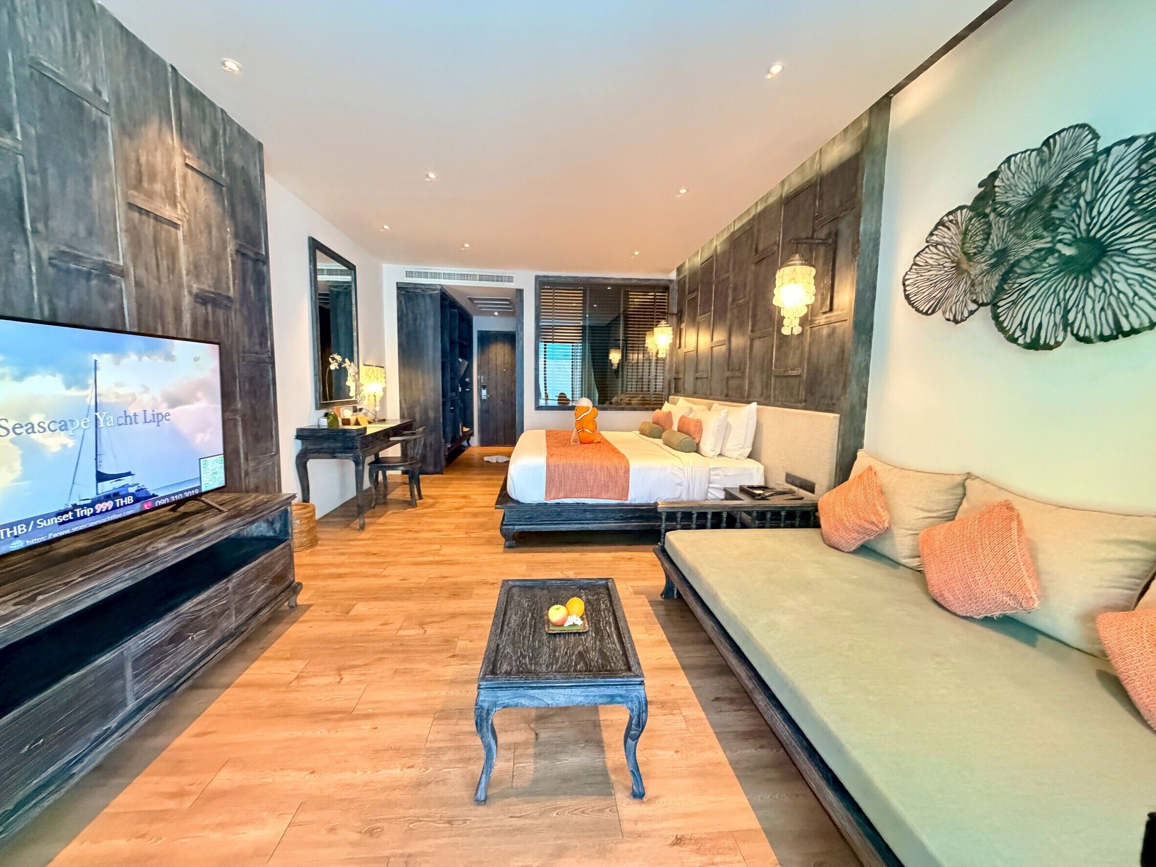A modern hotel room with a large bed, a sofa, a TV, and a desk.