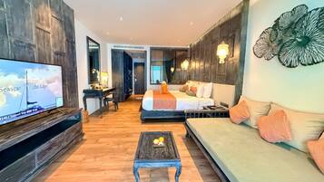 A modern hotel room with a large bed, a sofa, a TV, and a desk.