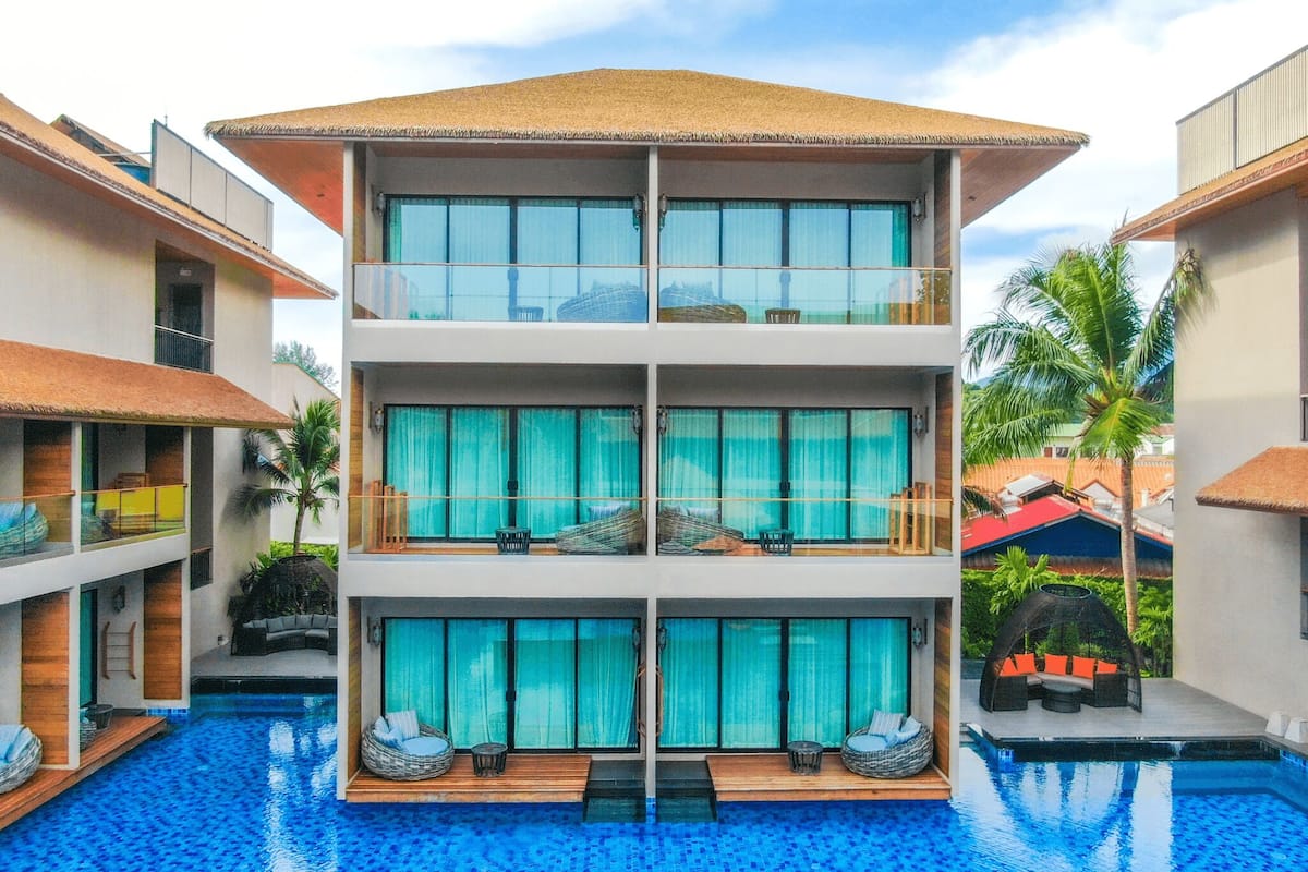 A multi-story hotel with a swimming pool in front.