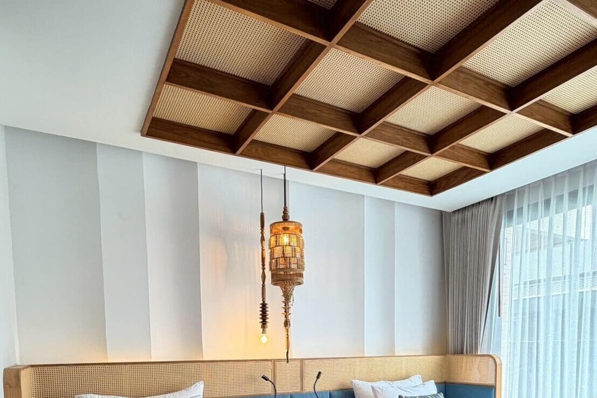 A hotel room with two beds, a wooden ceiling, and a hanging light fixture.