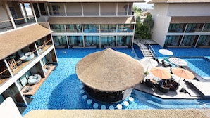 Un resort con varios balcones, una piscina central y mobiliario exterior bajo sombrillas.