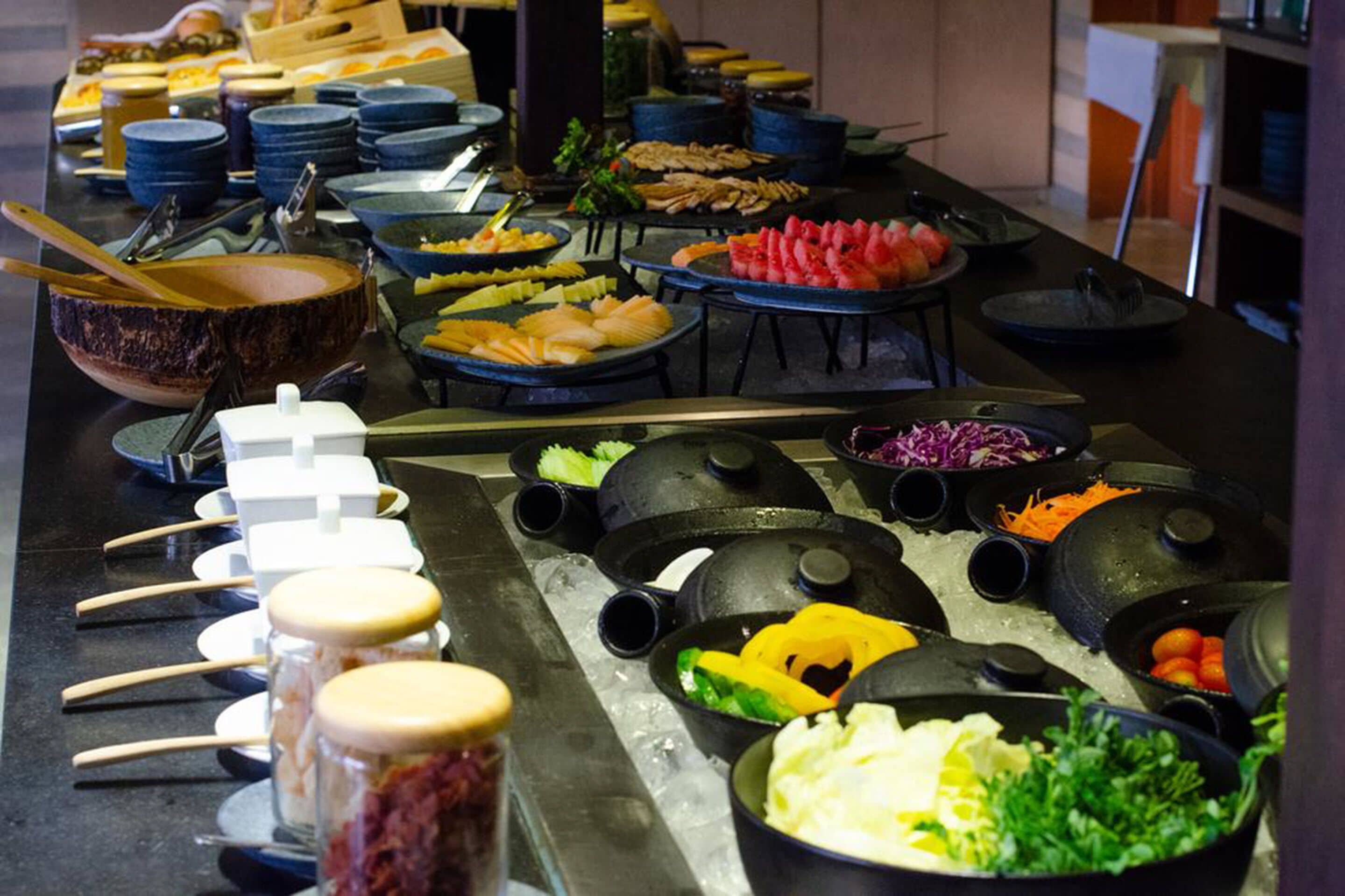 A buffet with various food items and utensils.