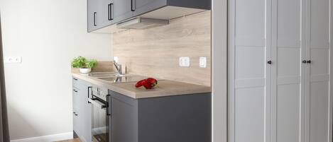 Una cocina moderna con armarios grises, encimera de madera y un pimiento rojo sobre la encimera.