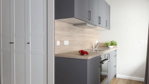 A modern kitchen with grey cabinets, a wooden countertop, and a red pepper on the counter. - Villa am Park (Binz)