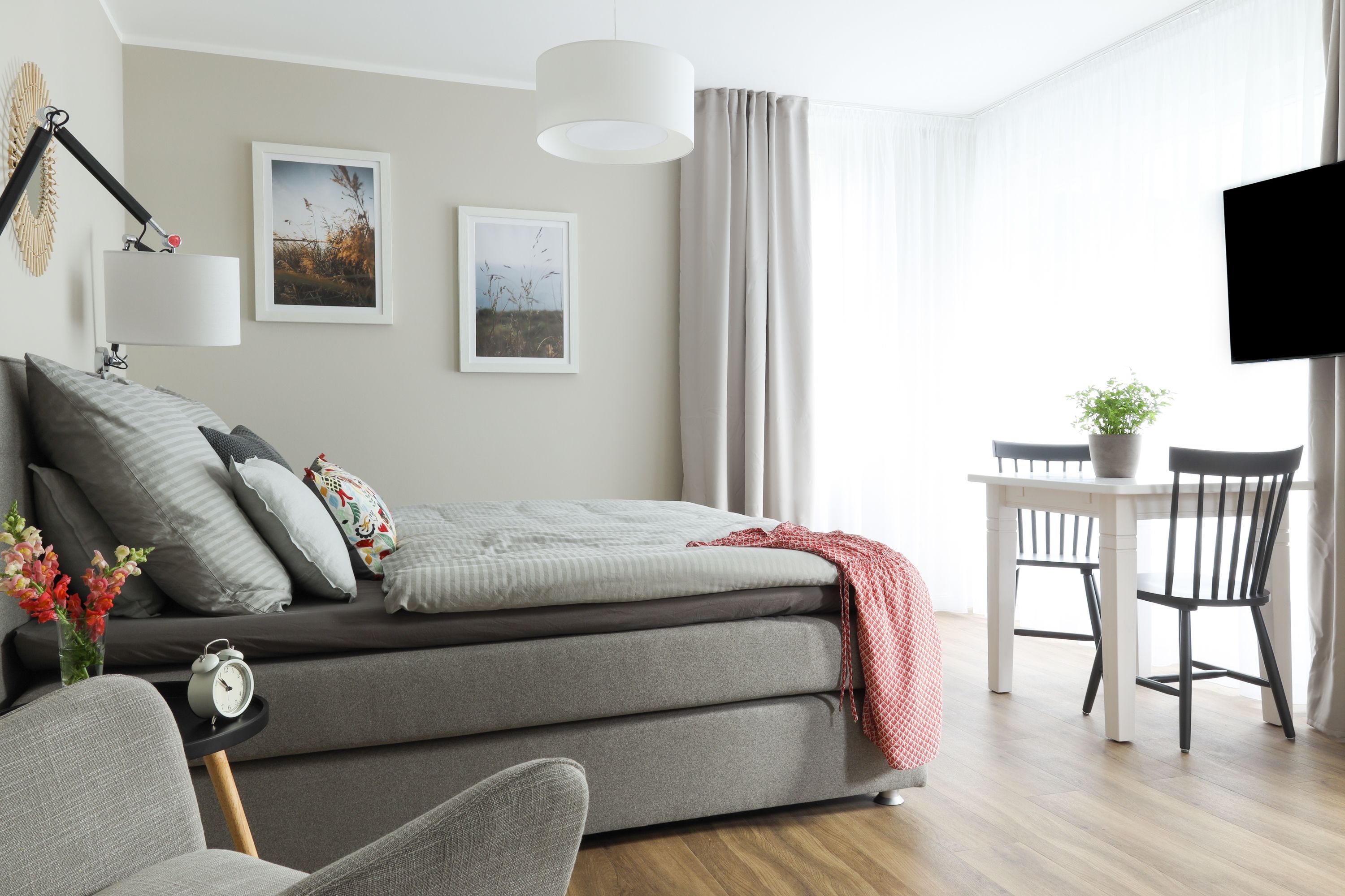 Une chambre à coucher moderne avec un lit, une table de chevet, une lampe et une œuvre d’art.