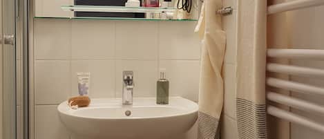 Un baño con un lavabo blanco, un espejo, un perchero para toallas y un secador de pelo.