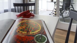 A dining area with a table, chairs, and a book open to a page with a food image. - Villa am Park (Binz)