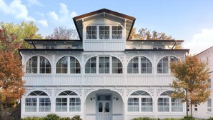 A two-story white building with multiple arched windows and a central entrance. - Villa am Park (Binz)