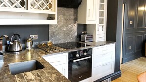 A modern kitchen with a black stove, white cabinets, and a marble countertop. - The Residence Sasco Apartments (Blackpool)