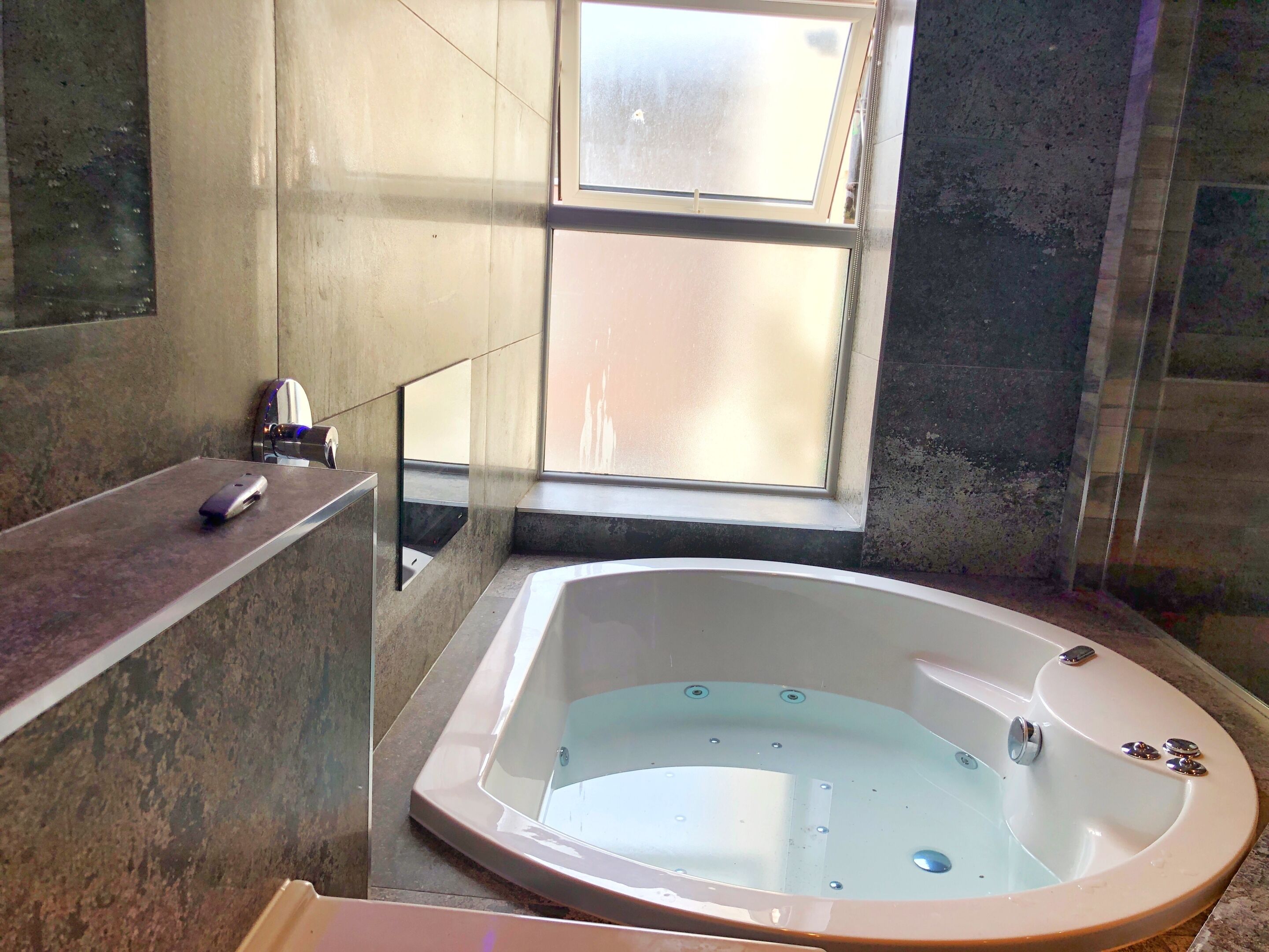 A modern bathroom with a freestanding bathtub, a mirror, and a window.