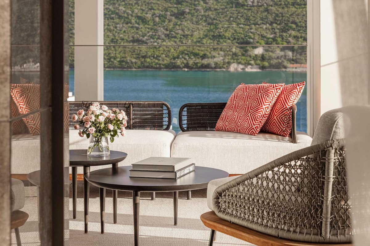 A modern outdoor seating area with wicker furniture, a round table with a book, and a vase of flowers.
