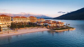 A waterfront hotel with multiple buildings, a pool, and a view of mountains. - One&Only Portonovi (Kumbor)