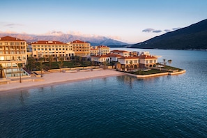 A waterfront hotel with multiple buildings, a pool, and a view of mountains. - One&Only Portonovi (Kumbor)