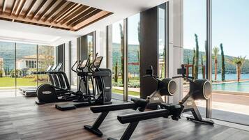 A modern gym with cardio machines, weightlifting equipment, and large windows offering scenic views.
