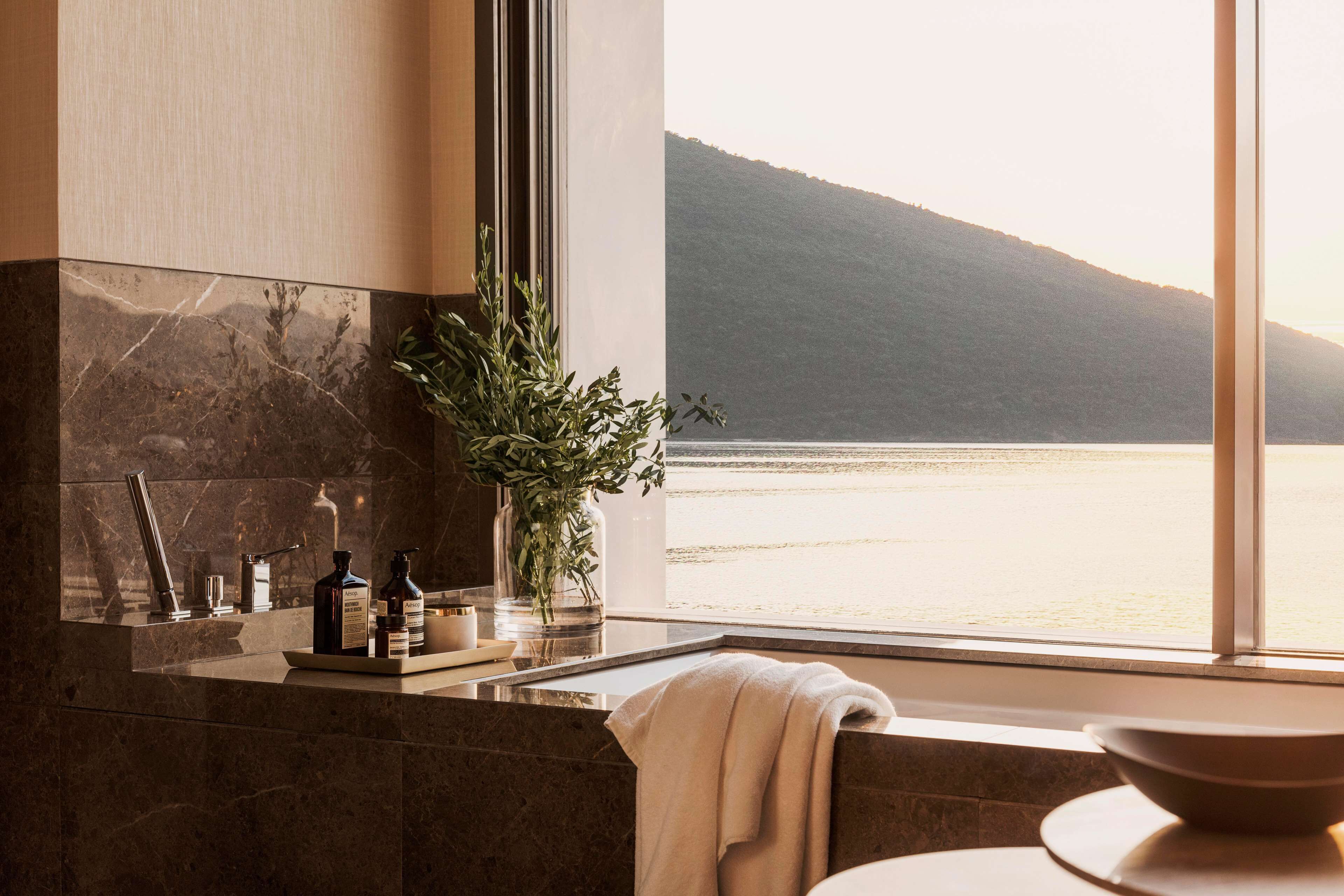 A bathroom with a large window, a sink, and toiletries.