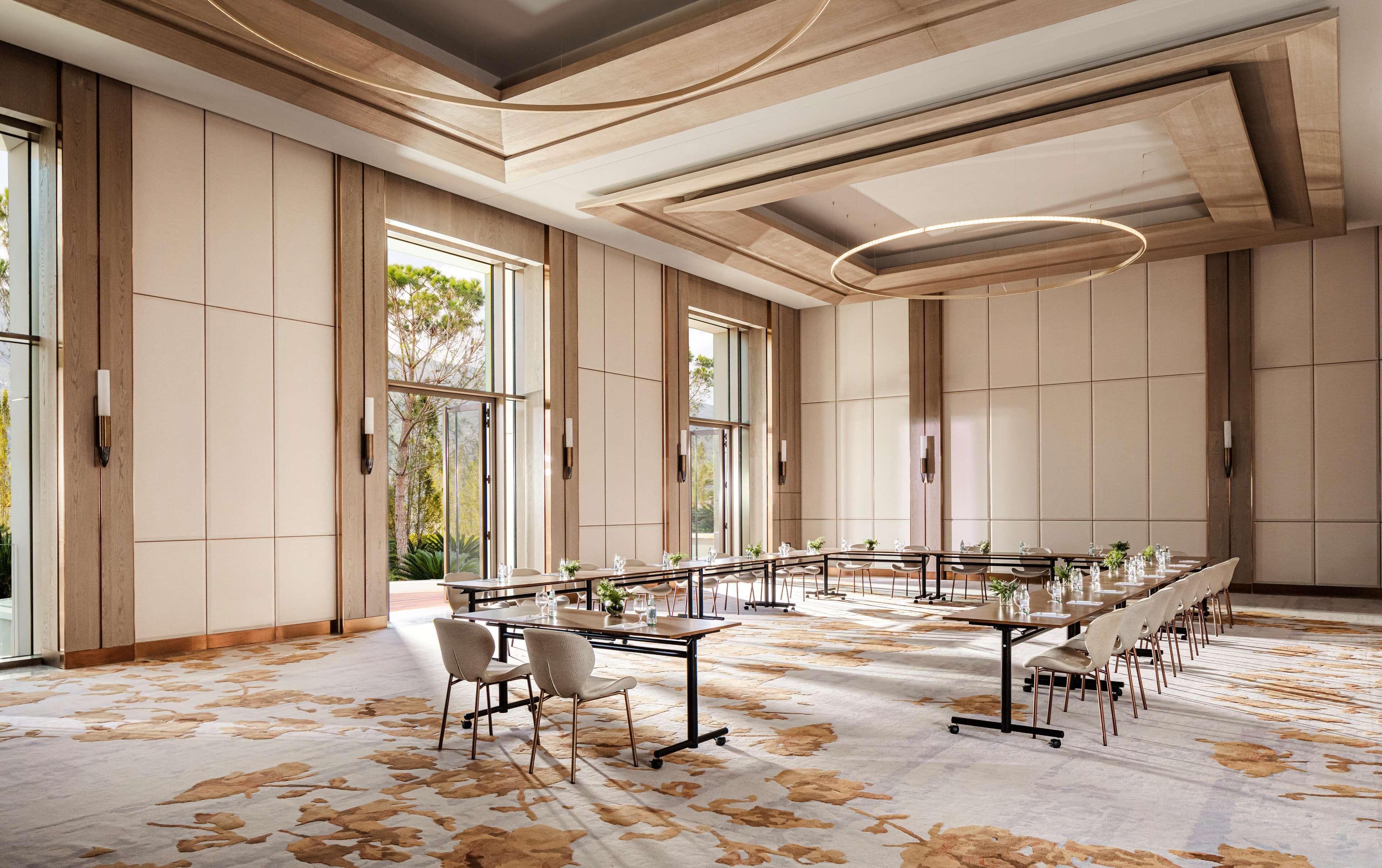 A spacious conference room with a long table, chairs, and a patterned carpet.