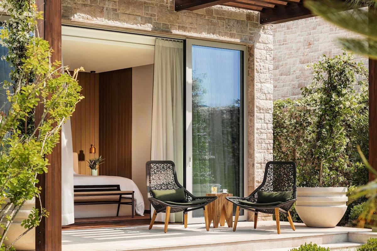 A modern outdoor seating area with two chairs, a table, and a large potted plant.