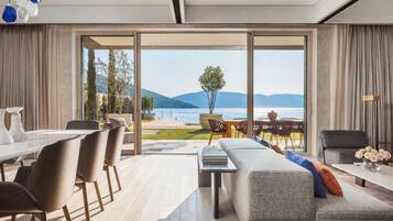 Una sala de estar moderna con un amplio ventanal corredero que da a un balcón con vistas al mar y a las montañas.