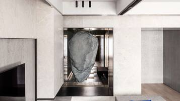 A modern interior with a large stone sculpture, a flat-screen TV, a sofa with cushions, and a patterned rug.