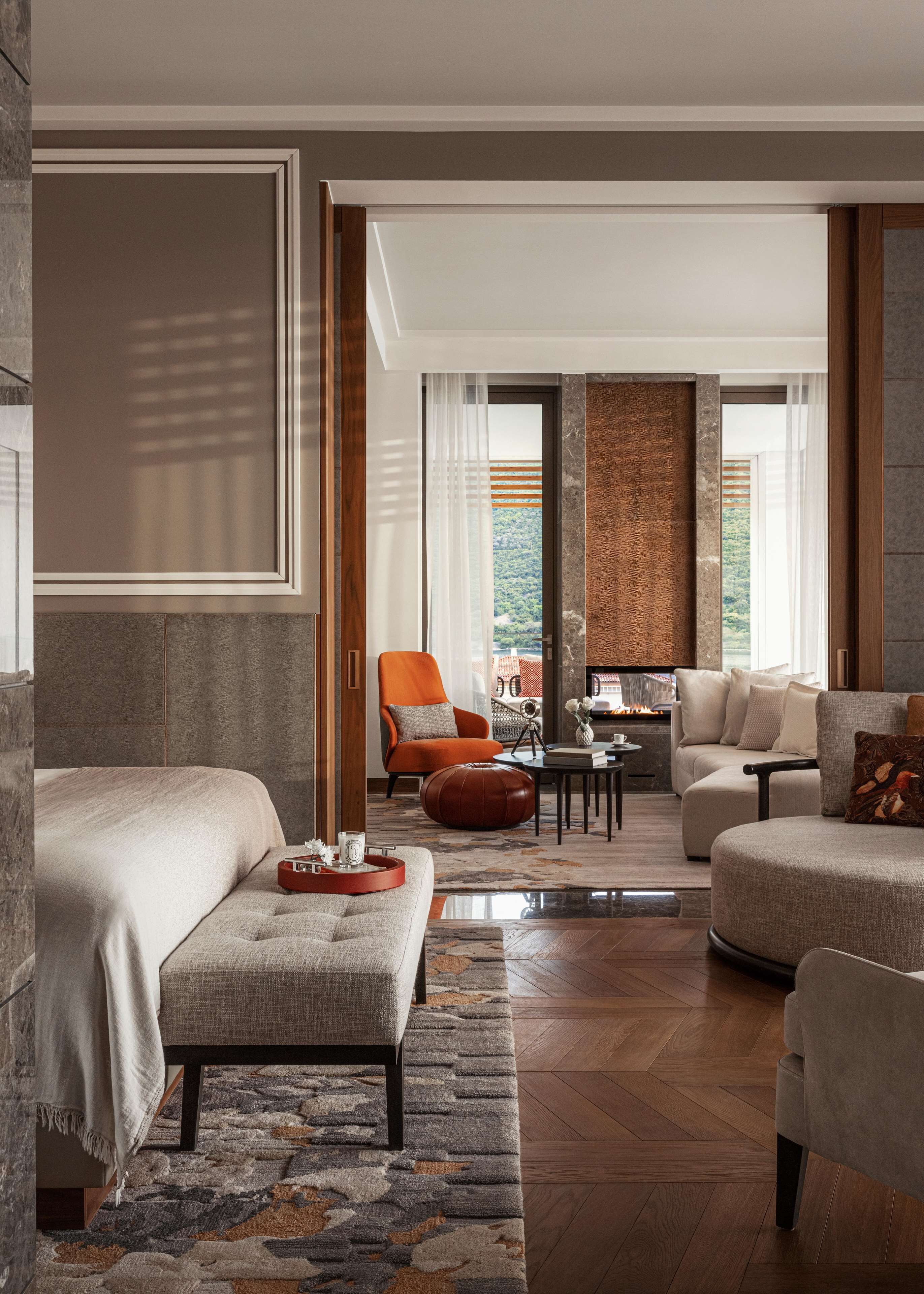 A modern hotel room with a bed, two sofas, a coffee table, and a view of the outdoors.