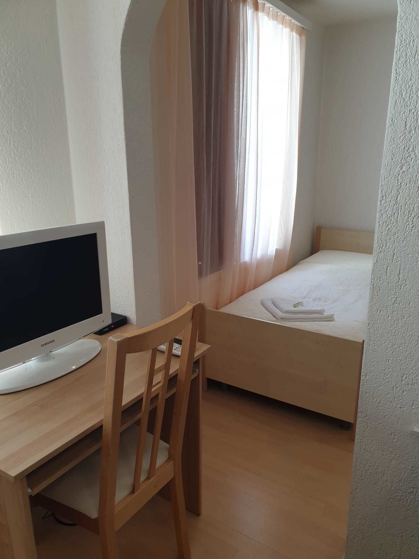 A bedroom with a bed, a desk with a computer, and a chair.