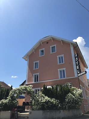 A hotel with a pink facade, multiple windows, and a sign reading "HOTEL EDELWEISS". - Hotel Edelweiss (Neuhausen am Rheinfall)