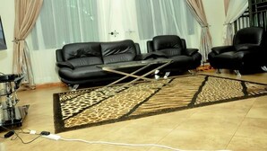 A living room with a sofa, two chairs, a coffee table, and a patterned rug. - Dorabo Tourist Hotel (Jinja)