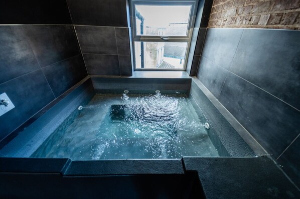 A modern bathroom with a freestanding bathtub, tiled walls, and a window providing a view of the outside.