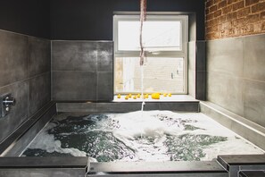 A bathtub with a window, a faucet, and rubber ducks. - The Loft Sasco Apartments (Blackpool)