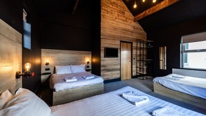 Una habitación de hotel moderna con techo de madera, dos camas, un vestidor amplio y un ventanal grande.