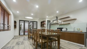 A dining area with a wooden table and chairs, a kitchen with a microwave and sink, and a sliding glass door leading to an outdoor area.