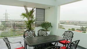 A balcony with a glass ceiling, a table with chairs, and potted plants.