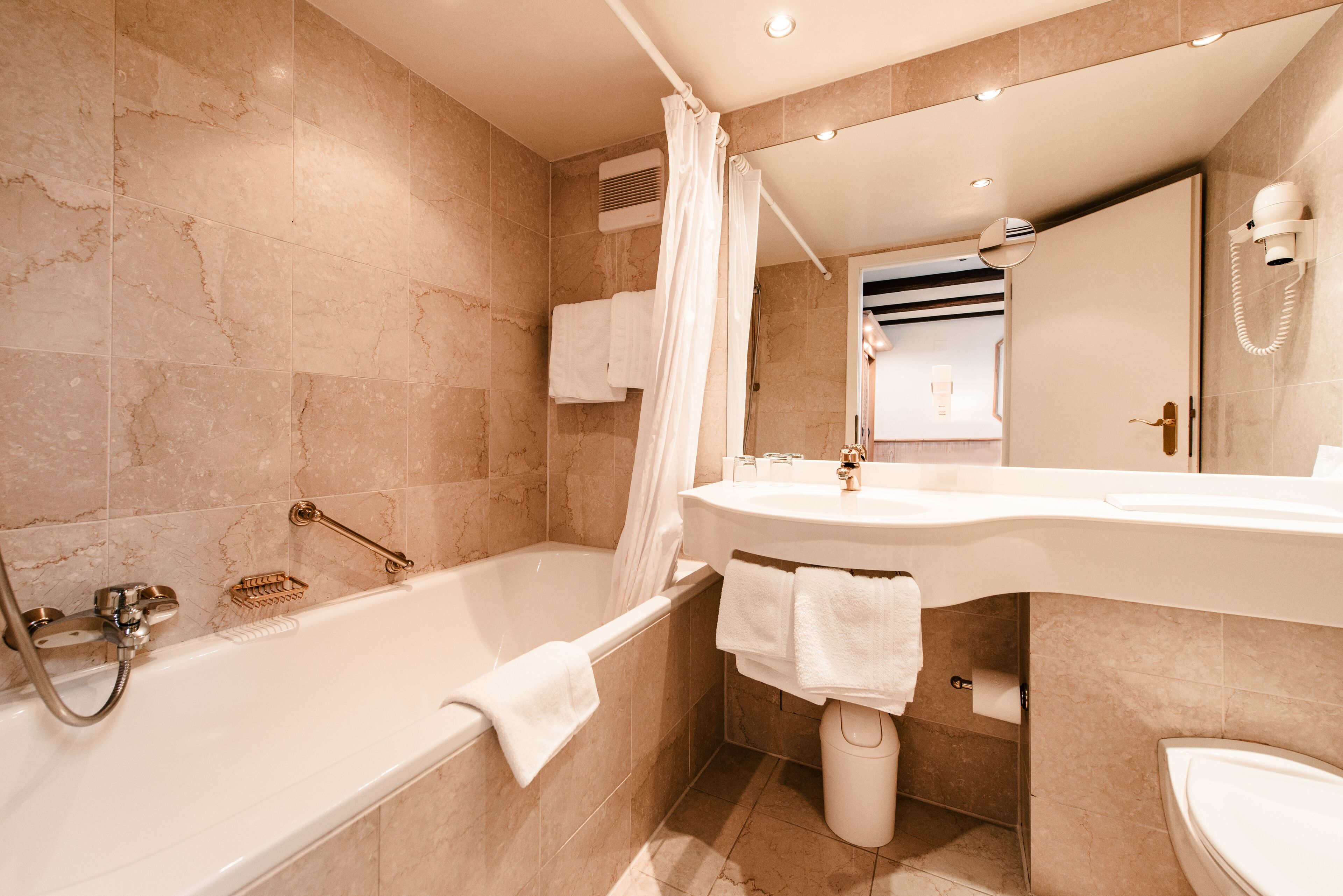 A modern bathroom with a bathtub, shower, and toilet.