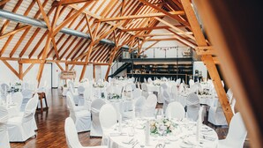 A large hall with high wooden beams and multiple round tables set up for a formal event. - Hotel Ochsen (Merklingen)