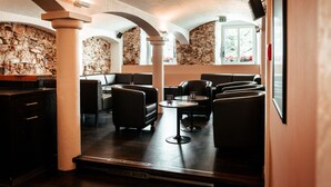 A restaurant with stone walls, black leather seating, and a wooden counter. - Hotel Ochsen (Merklingen)