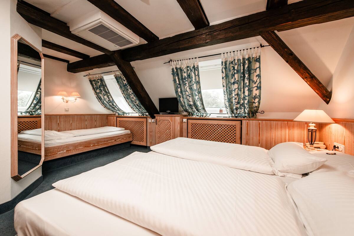 A bedroom with a loft bed, a large mirror, and a window with curtains.
