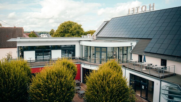A modern hotel with a flat roof, large windows, and a balcony with outdoor seating. - Hotel Ochsen (Merklingen)