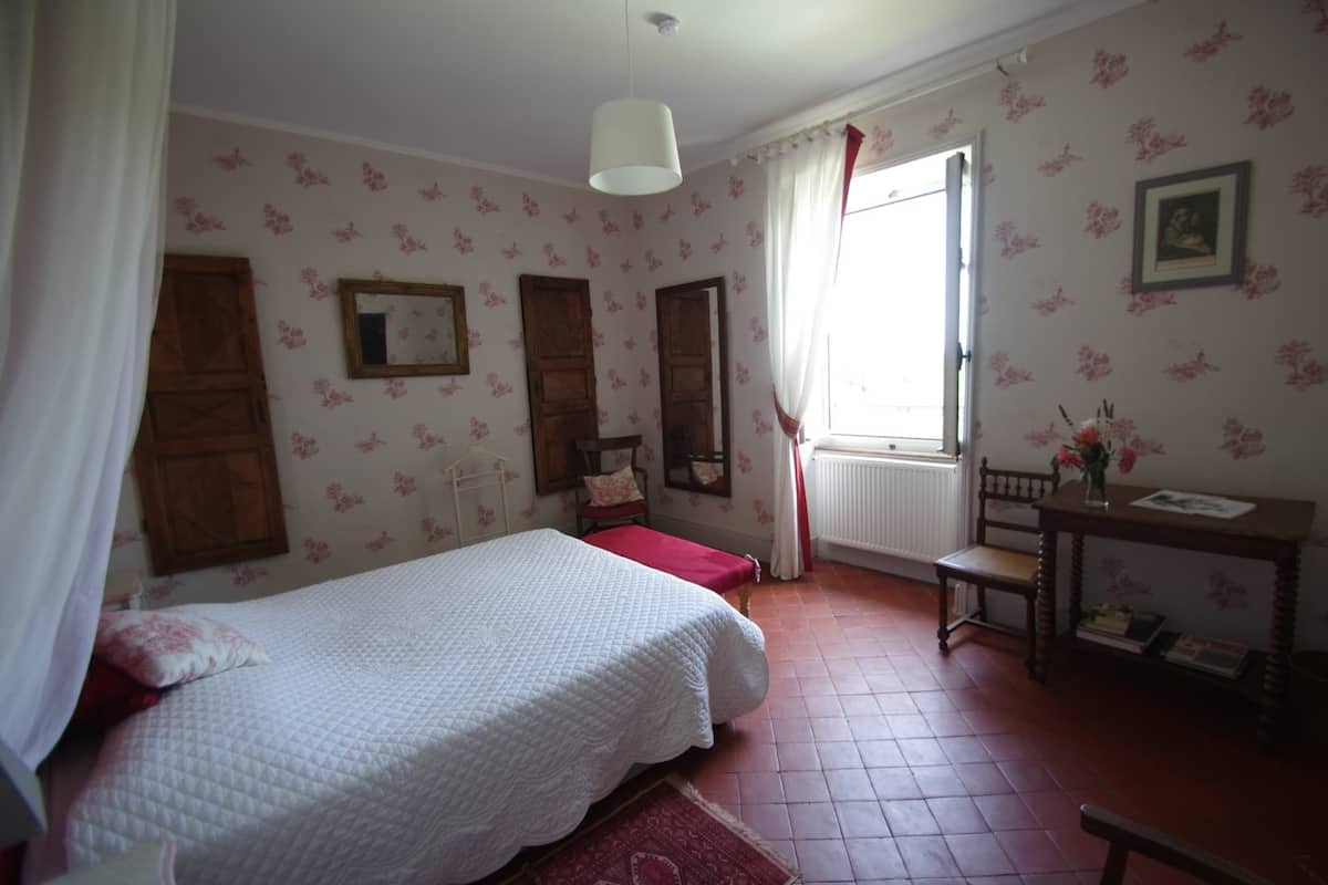 Ein Schlafzimmer mit Bett, Schreibtisch und Fenster.